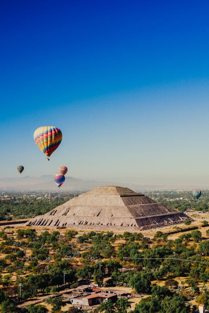 a group of hot air balloons flying over a pyramid
